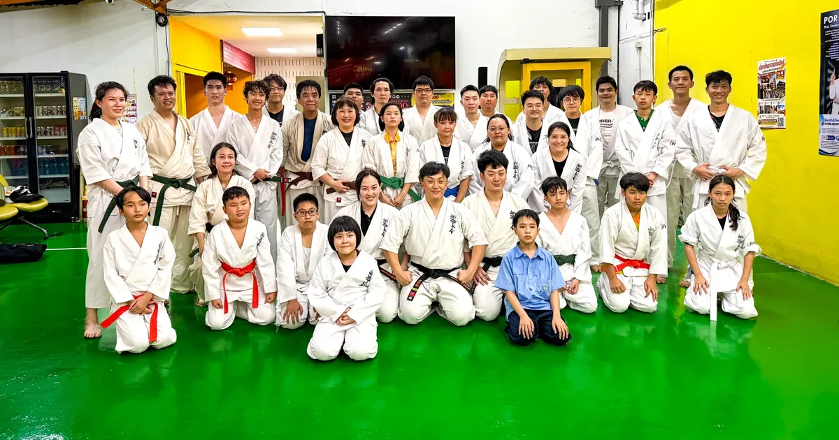 ภาพหมู่ผู้เรียนคาราเต้ IMAC Dojo หลังการฝึก เห็นเข็มขัดหลายสีทั้งขาว แดง ส้ม เขียว น้ำตาล และดำ